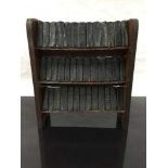 A late nineteenth/early twentieth century miniature oak bookshelf, holding 39 miniature novels,