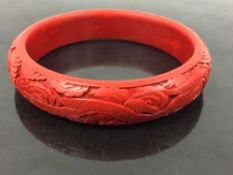A Chinese cinnabar bangle, with dragon carved decoration, internal diameter 6.5 cm.