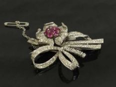 An 18ct white gold diamond encrusted bow brooch of floral design set with a cluster of seven rubies,