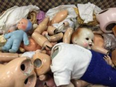 A trunk containing various vintage doll parts, bisque heads, limbs and clothing.