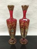 A pair of late Victorian Bohemian ruby glass vases, hand gilded and painted with floral decoration,