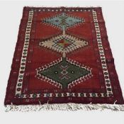 A wool Eastern carpet on red ground with geometric patterns, 170 cm x 122 cm.