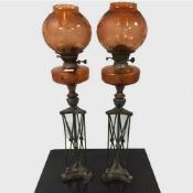 An unusual pair of Arts and Crafts bronze and orange etched glass oil lamps,