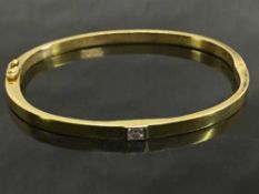 An 18ct gold shaped bangle, set with an emerald cut diamond, diameter 5 cm x 6 cm, 23.3g.