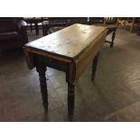 An Edwardian pine drop leaf kitchen table fitted a drawer