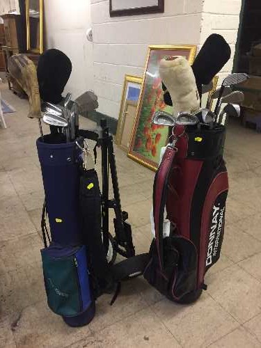 Two bags of assorted golf clubs and a golf trolley