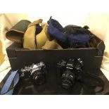 A box of camera bags, Olympus OM-1 camera with lens, Nikon F90X camera, Sony cam corder,