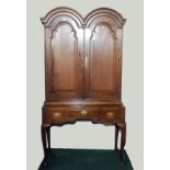 Early Georgian oak cupboard, the double domed top above pair of fielded panel doors enclosing