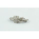 Diamond brooch with flowerhead, leafage & sprays of baguettes & brilliants, in platinum.