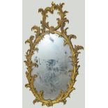 Early 19th century giltwood mirror, the oval glass in foliate scroll frame with foliate pediment,