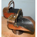 Two Victorian copper coal buckets of helmet form on domed circular foot with swing handles,