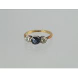 Three stone ring with an oval sapphire flanked by two diamond brilliants, millegrain set, '18ct`,