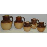 Graduated set of five Doulton Lambeth stoneware jugs of baluster form with brown glazed necks,
