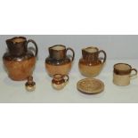 Three graduated Doulton Lambeth stoneware jugs of baluster form with brown glazed necks,