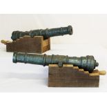 A matching pair of cast iron cannon barrels 55cms in length mounted on solid oak carriages
