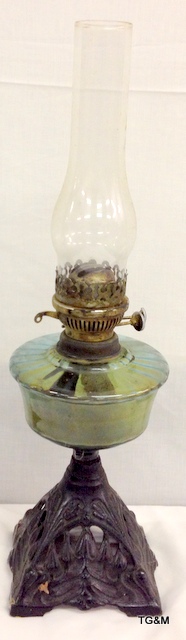 A wrought iron and glass oil lamp with chimney 58cm