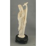 Carved ivory figure of Guanyin pouring water from a bottle set on a wooden base. 23cm high