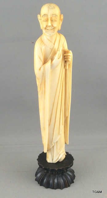 A carved ivory figure of a sage on a wooden stand 20cm high.