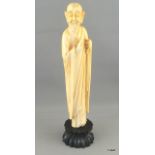A carved ivory figure of a sage on a wooden stand 20cm high.
