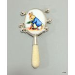 A silver babies rattle with enamel plaque depicting peter rabbit and bone handle