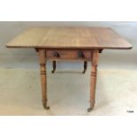 A mahogany Pembroke table on turned supports with a drawer at both ends and brass casters