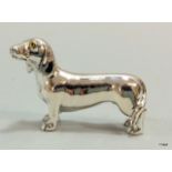 A solid silver sausage dog with citrine eyes