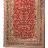 An Iranian room size rug with blue borders and central red pattern 255 x 155cm