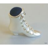 A silver pincushion in the form of a ladies boot inset with a sapphire