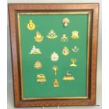 A framed display of 16 British military cap badges