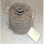 A roll of WW2 Barbed Wire with carry handles. Having a museum label from the Whitehall Theatre of