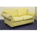 A modern Laura Ashley two-seat settee, upholstered in yellow cotton, on turned legs and castors,