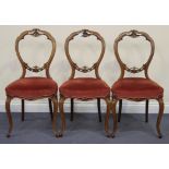 A set of three Victorian spoon back dining chairs with carved and pierced decoration, raised on