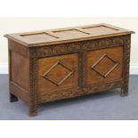 An early 20th Century oak coffer, the panelled lid and front with carved and moulded decoration,