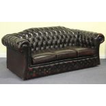 A late 20th Century burgundy buttoned leather Chesterfield style three-seat settee with a shaped