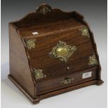 An Edwardian oak and brass mounted desk top letter box, the hinged sloping lid enclosing shaped