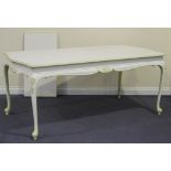 A French white painted oak extending dining table with a single extra leaf, raised on cabriole legs,