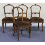 A set of four late Victorian walnut spoon back dining chairs with carved foliate decoration, the