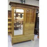 An Edwardian walnut wardrobe, the moulded pediment above a full-length mirror flanked by a