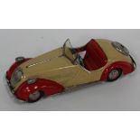 A German tinplate clockwork open top tourer, finished in red and cream, with hand brake, forward and