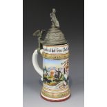 A German porcelain stein, the hinged pewter lid surmounted with a soldier above an eagle thumbpiece,