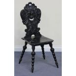 A 19th Century ebonized side chair, the back carved with a mask and scrolls, raised on turned