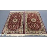 A pair of Indian rugs, late 20th Century, each claret field with an ivory medallion, within ivory