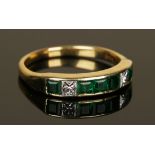 An 18ct gold, emerald and diamond half-hoop ring, mounted with five square cut emeralds and two