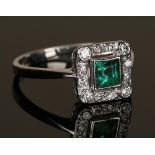 An emerald and diamond ring, the square cut emerald in an openwork surround, mounted with circular