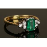 An 18ct gold, emerald and diamond ring, claw set with the cut cornered rectangular step cut