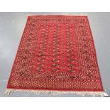 A Pakistan bokhara style rug, mid/late 20th Century, the red field with three columns of guls,