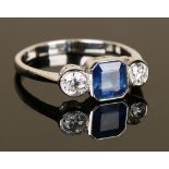 A sapphire and diamond three stone ring, mounted with the cut cornered square cut sapphire between