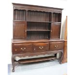 An early 20th Century George III style oak dresser, the shelf back above three drawers, raised on