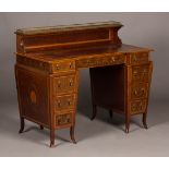 A late Victorian mahogany and satinwood crossbanded inverted breakfront writing desk by Edwards