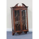 A 20th Century reproduction mahogany hanging wall cabinet, the swan neck pediment above two glazed